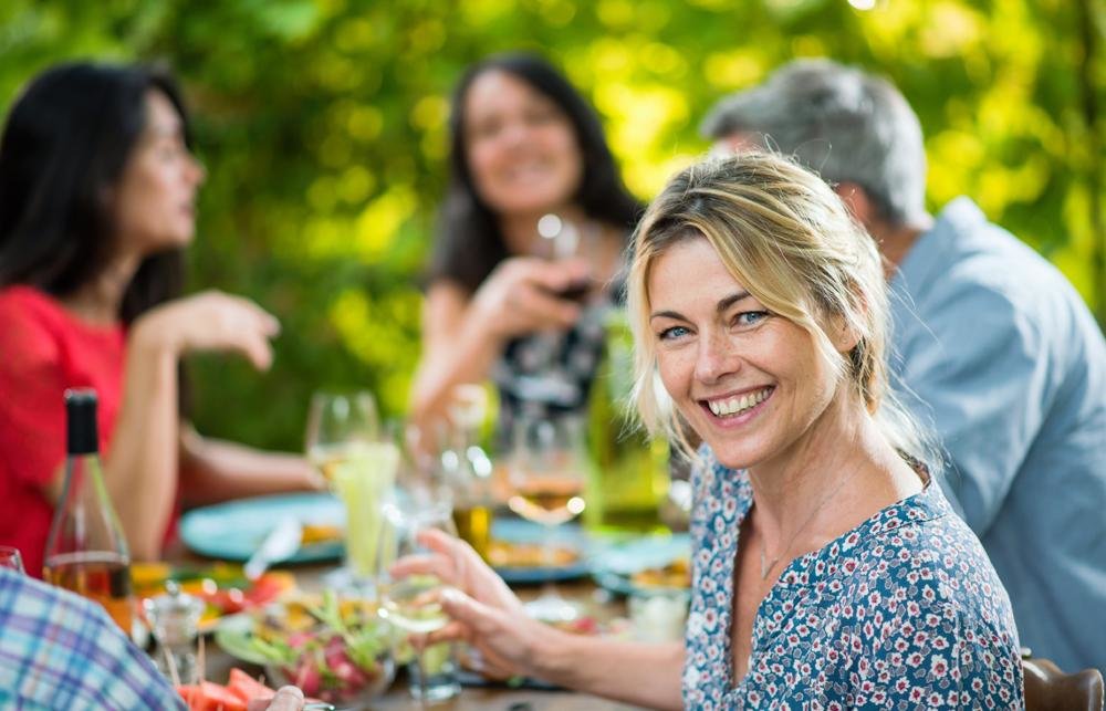 A smiling woman at a table with some friends.